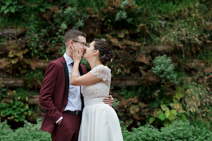 A bride and groom share a kiss in front of a garden wall in Philly.